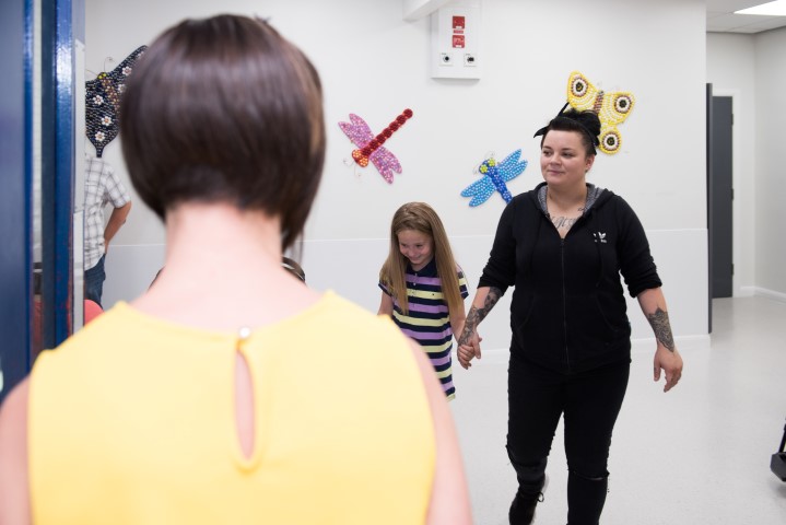 A girl and her mum walk through a doorway