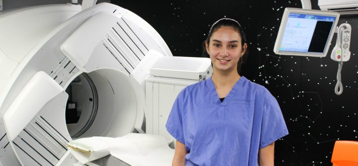 Female apprentice stood in front of radiology scanner