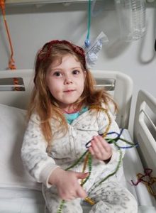 Young girl in hospital bed playing with tinsel