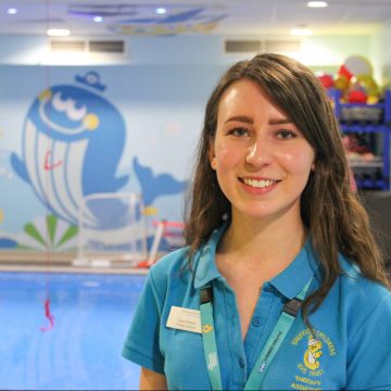 Picture of a therapy assistant by a brightly decorate hydrotherapy pool