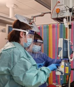 nurses in full PPE next to a drip