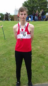 Dan in red top and black leggings with medal round his neck from a sporting competition