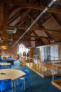 school hall with blue chairs and wooden tables - the ceiling is like a chapel